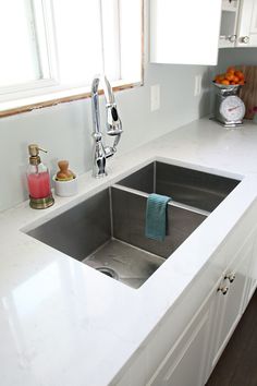 a kitchen sink sitting under a window next to a counter