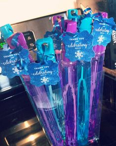 there are three purple and blue toothbrushes in the vase with snowflakes on them