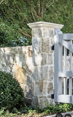 a stone wall with a white wooden gate