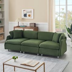 a living room with a green couch and coffee table in front of a large window