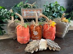 four pumpkins are sitting next to each other on a table with leaves and ribbons