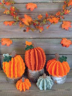 three small pumpkins sitting next to each other on top of a wooden table with autumn leaves