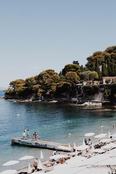 the beach is crowded with umbrellas and people swimming in the blue water near an island