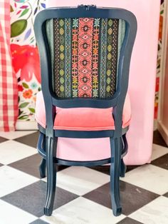 a blue chair sitting on top of a black and white checkered floor next to a pink wall