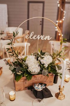 a wooden box with white flowers and greenery on it is sitting on a table