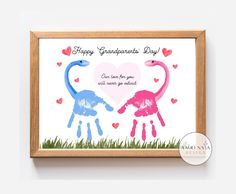 two pink and blue handprints are in front of a wooden frame that says happy grandparents day