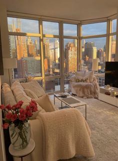 a living room filled with furniture and large windows overlooking the cityscape in the distance