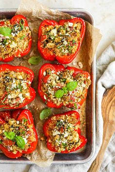 six stuffed red peppers in a baking pan with herbs and seasoning on top, ready to be baked