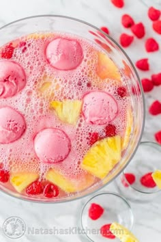 a bowl filled with fruit and ice cream next to some raspberries on the table