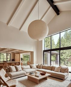 a living room filled with lots of furniture next to large windows and floor to ceiling windows