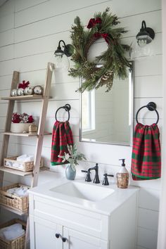 a bathroom decorated for christmas with wreaths on the wall and towels hanging above the sink