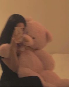 a blurry photo of a woman holding a teddy bear in front of her face