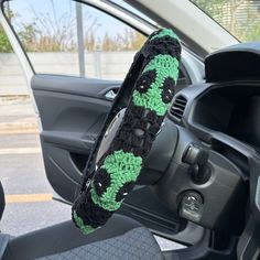 the steering wheel cover is decorated with green and black crochet