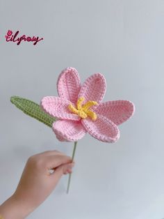 a crocheted pink flower being held by a child's hand with the word lily written on it