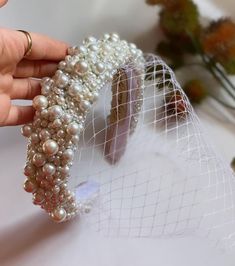 a woman is holding a veil with pearls on it