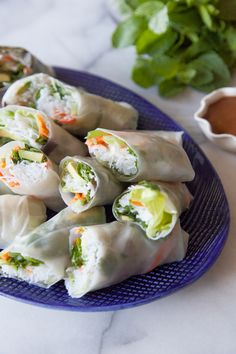 a blue plate topped with dumplings covered in veggies next to dipping sauce