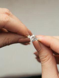 a woman is holding an engagement ring in her hand