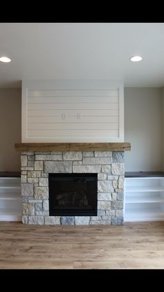 an empty living room with a fireplace and built in shelves