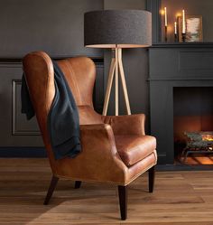 a brown chair sitting in front of a fireplace with a blanket on it's back