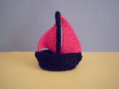 a pink and black knitted sailboat sitting on top of a table