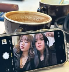 a cell phone sitting on top of a table next to a cup of coffee