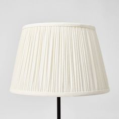 a white lamp with a black base and pleated lampshade on the bottom