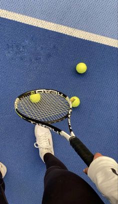 a person holding a tennis racquet on top of a blue court with balls