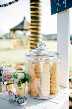 a table topped with a glass jar filled with bananas and ice cream cones next to a chalkboard sign