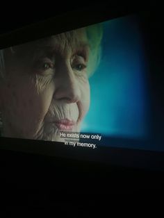 an old woman's face is projected on a television screen with the caption, life ends now only in my memory