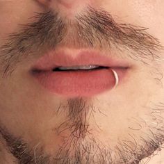 a close up of a mans nose with a ring on it's lip and beard