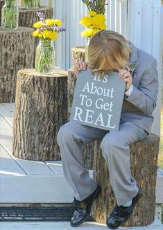 a young man sitting on a tree stump holding a sign that says it's about to get real