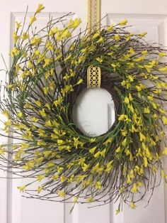 a wreath with yellow flowers hanging on a door