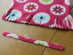 a pink and white flowered hat sitting on top of a wooden floor next to a pair of scissors