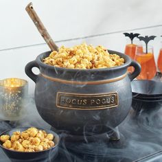 a large pot filled with popcorn sitting on top of a table next to two glasses