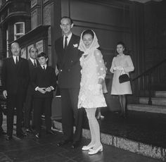 a man and woman standing next to each other in front of some people on steps