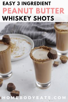 three glasses filled with peanut butter whiskey shots on top of a white table next to cookies