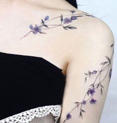 a woman's shoulder with purple flowers on it