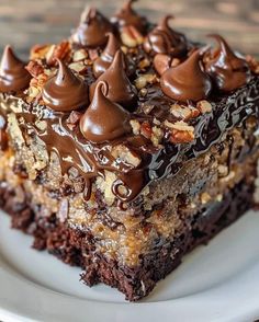 a piece of cake with chocolate frosting and nuts on top sitting on a plate