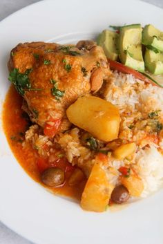 a white plate topped with rice, meat and veggies next to cucumbers