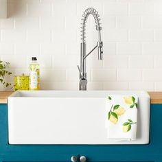 a white sink sitting under a faucet next to a kitchen counter top with yellow flowers on it