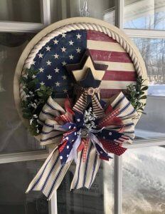 an american flag wreath hanging on a window sill with the stars and stripes painted on it