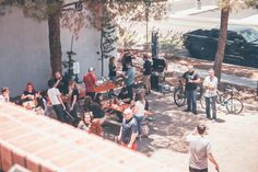 a group of people standing around a table with food and drinks on it in front of a building