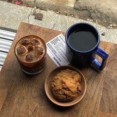 two cups of coffee and some cookies on a wooden table next to each other,