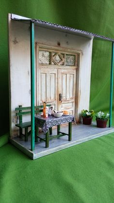 a doll house with a table and bench in the middle of it on a green background