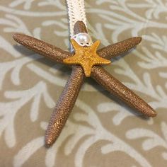 a starfish with pearls hanging from it's side on a tablecloth background