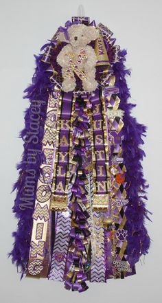 a purple and gold dress with a teddy bear on it's chest, hanging from the wall