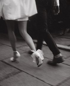 black and white photograph of people walking down the street with their feet in the air