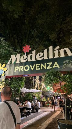 people are sitting at tables under the sign for medellin's provenza