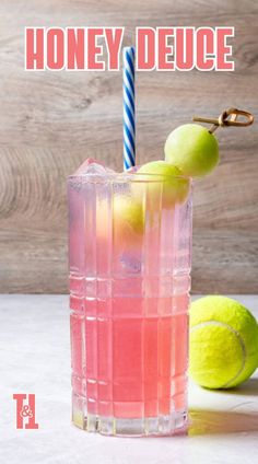 a pink lemonade drink in a tall glass next to a tennis ball