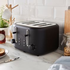 a black toaster sitting on top of a counter next to a plate with food